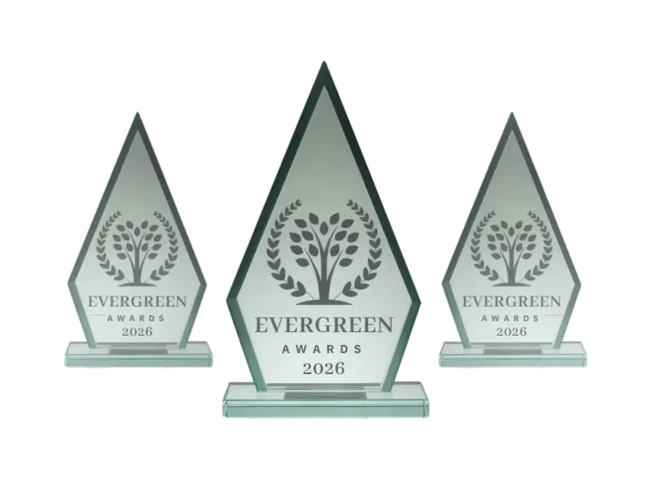 Three glass Evergreen Awards trophies with a tree emblem and 'Evergreen Awards 2026' inscription on each pedestal (center trophy largest).